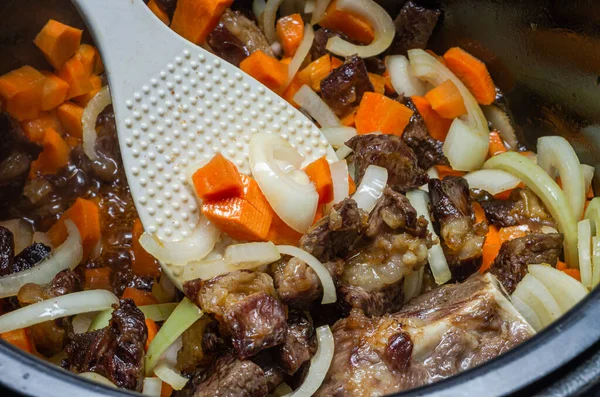 stock image The cook fries lamb meat with onions and carrots in a multicooker pan