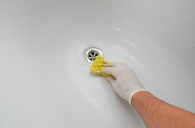 Hizmetçi banyoda banyo küvetini kimyasallarla yıkıyor.