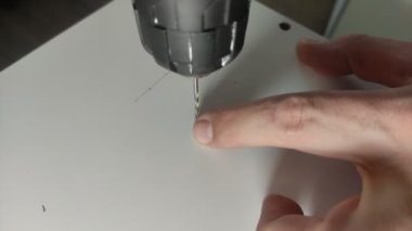 Mobilya ustası, mobilya tabağında vidalar için elektrikli matkapla delik açıyor.