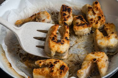 Aşçı tavada turnabalığı keser ve kızartır.