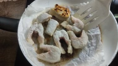 Aşçı tavada turnabalığı keser ve kızartır.