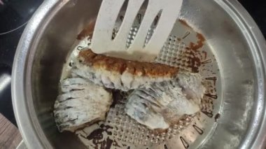 Aşçı kızartma tavasında haç balığı kızartıyor.