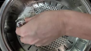 Aşçı kızartma tavasında haç balığı kızartıyor.