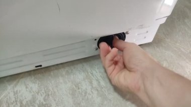 Usta tamirci servis sırasında çamaşır makinesinde filtre temizler