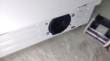 Usta tamirci servis sırasında çamaşır makinesinde filtre temizler
