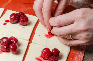 The cook wraps cherries in dough for cookies