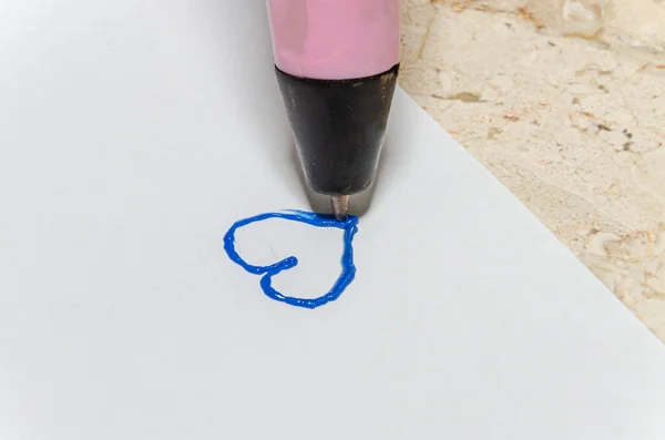 A person draws a heart with a 3d pen
