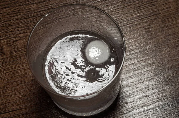 A man puts one effervescent tablet in a glass that dissolves in water