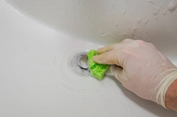Housekeeper washing bathtub with lime scale cleaner in bathroom