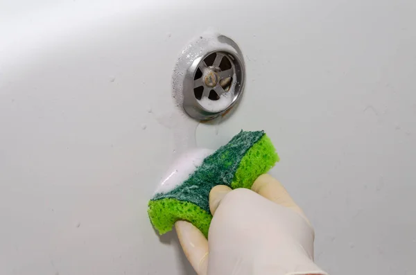 Housekeeper washing bathtub with lime scale cleaner in bathroom