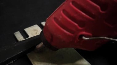 Usta, parçaları yapıştırıcı çubuğuyla yapıştırıyor.