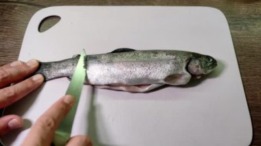 Aşçı bir kesme tahtasıyla alabalık keser.