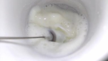 Aşçı süt köpüğünü karıştırıcıyla çırpar.