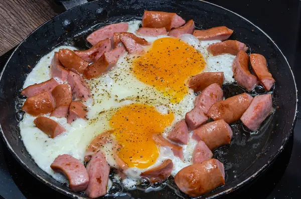 Fried eggs with sausages in a frying pan