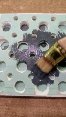 Bir ressam alçı tahtayı fırça ve boyayla boyuyor, dikey video.