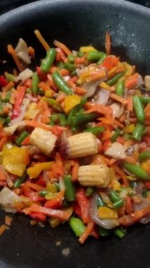Vegetables are fried in a wok pan
