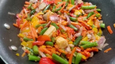 Vegetables are fried in a wok pan