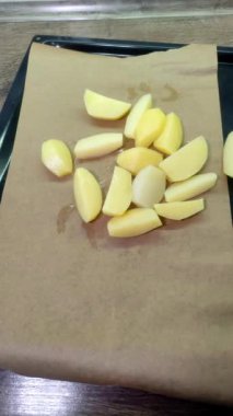 Bir aşçı pişirmek için patatesleri tepsiye koyar.