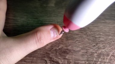 Manikürcü kuaförde müşterinin tırnaklarını kesiyor.