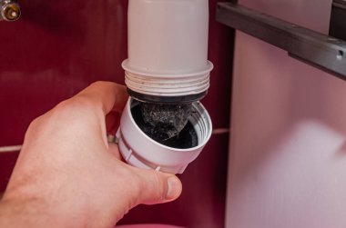 Muslukçu tıkanmış lavaboyu temizler.