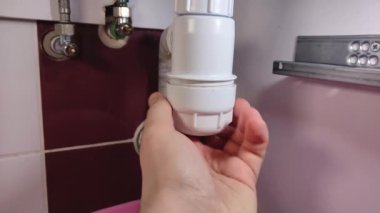 Muslukçu tıkanmış lavaboyu temizler.