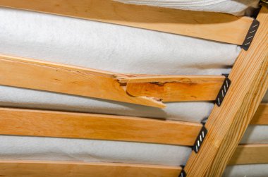 Yatağın üstünde, yatağın altında, kırık ahşap bir bölme.