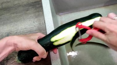 Mutfakta bir şef kabak soyuyor.