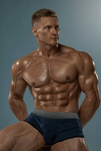 Bodybuilder Uomo Posa Mentre Seduto Una Sedia Studio Pantaloncini Mostrando — Foto Stock
