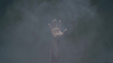 Bir adamın eli, eli boş bir arka planda dumanla çevrilir ve aşağı iner.