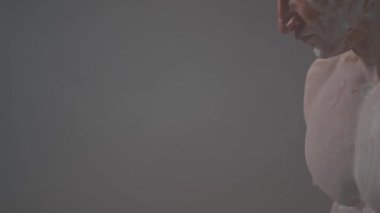 Vücut geliştirici yetişkin kaslı erkek model antik Yunan heykelleri tarzında poz veriyor. Bir adam, dumanla çevrili bir düşünür gibi poz verir..
