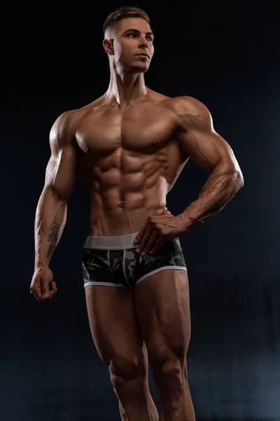 迷人的性感健美运动员在黑色背景的演播室里穿着短裤 表现出肌肉强健的身体 体操和身体美学中的刻苦工作概念 — 图库照片