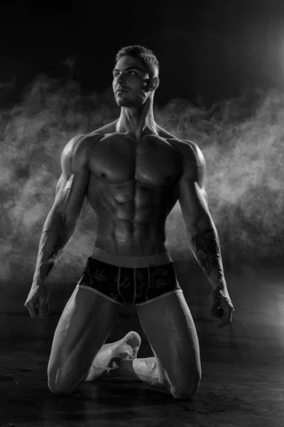 Egy Erős Atlétikus Férfi Térden Állva Pózol Fekete Stúdióban Sportos — Stock Fotó