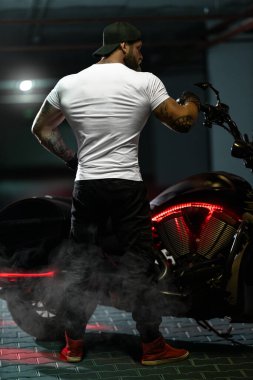 Seksi, yakışıklı, çekici, kaslı spor spor spor spor mankeni, park yerinde vahşi, güzel motosikletli, sırtı çerçeveli, motosikletli bir motosikletli.