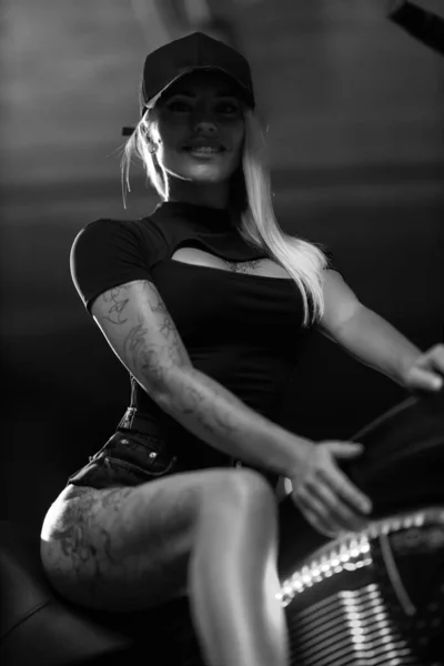 在停车场的摩托车上有一个性感的金发女人 脖子上有一条敞开的领带 摩托车上有纹身的漂亮健身模特 黑白照片 — 图库照片