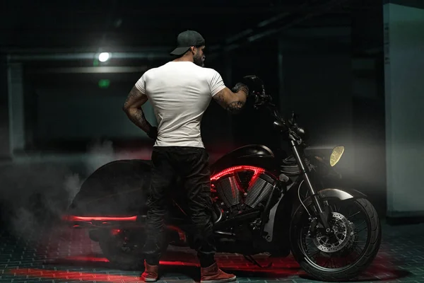 Seksi, yakışıklı, çekici, kaslı spor spor spor spor mankeni, park yerinde vahşi, güzel motosikletli, sırtı çerçeveli, motosikletli bir motosikletli.