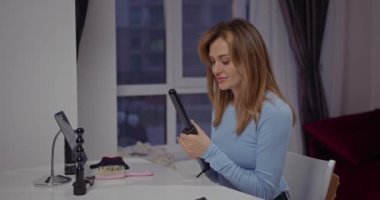 Güzel bir kız çıkar ve saç şekillendirme için saç maşası takar.