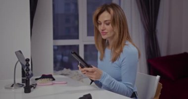 Masadaki güzel sarışın kız saç maşasını alır ve bağlarını değiştirir, bukleleri seçer.