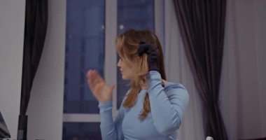 Genç ve güzel bir kadın saçını pencerenin kenarına kıvırmak için hazırlıyor.