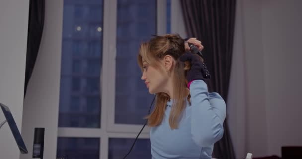 아름다운 금발은 창문으로 아이언으로 그녀의 머리를 — 비디오