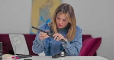 Güzel sarışın bir kız saç stili ve bukleler yaratmak için saç maşasına bağlanır.