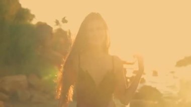 Gün doğumunda huzurlu sahilde uzun boylu güzel bir kız, altın güneş ışığı onu sıcak dalgalarla yıkarken sevinçle kıyıya doğru süzülüyor.