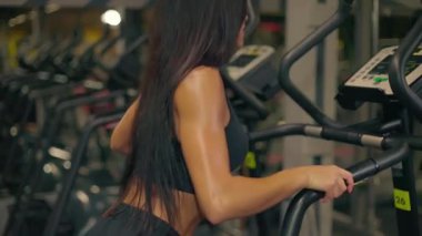 Kız akşam saatlerinde spor salonunda Stepper 'a kardiyo çalışması yapıyor. Egzersizlerine odaklanıyor. Formunu ve genel sağlık seviyesini arttırıyor..