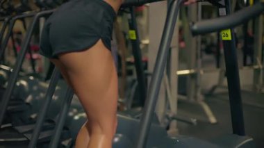 Kız Stepper jimnastik salonunda egzersiz yapıyor. Formunu ve gücünü geliştirmeye odaklanıyor. Spor salonu idmanlar için motive edici bir ortam sağlıyor..