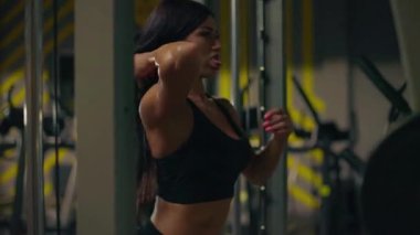 Kız, tekniğini ve gücünü vurgulayan halterlerle meşgul. Spor salonu modern ekipmanlara sahip ve fitness meraklıları için enerjik bir ortam sağlıyor..