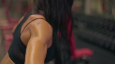 Spor salonunda, halter sırasına girmiş bir kız kuvvet eğitimine olan bağlılığını gösteriyor. Atmosfer fitness ve sağlığa olan bağlılığın altını çiziyor..
