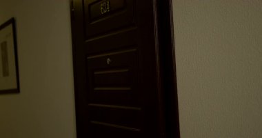 Güzel sarışın kadın ön kapıyı açıyor ve iyi aydınlatılmış bir koridora giriyor. Sahne, hoş bir atmosferde tesadüfi bir zarafeti yakalar..