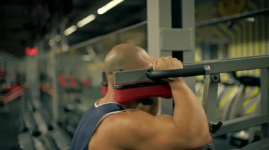 İyi donanımlı spor salonundaki kel sakallı adam formuna konsantre olurken bacak egzersizleri yapıyor. Atmosfer enerjiktir ve fitness için idealdir..