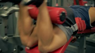 Atletik kel adam sakalı spor salonunda bacak egzersizlerini tamamlıyor. Güç antrenmanına odaklanıyor. Bacak kıvırıyor..