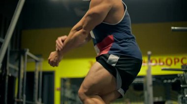 Kel adam bacak egzersizi yapar. Spor yapar. Güç antrenmanına odaklanır. Atmosfer arka planda akşam egzersiz ekipmanlarını yansıtıyor. Kameraya poz ver..