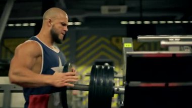 Kel sakal, iyi donanımlı spor salonunda ağırlık kaldırırken bacak egzersizlerine odaklanır. Ağırlıkları bacak pres makinesine asar.